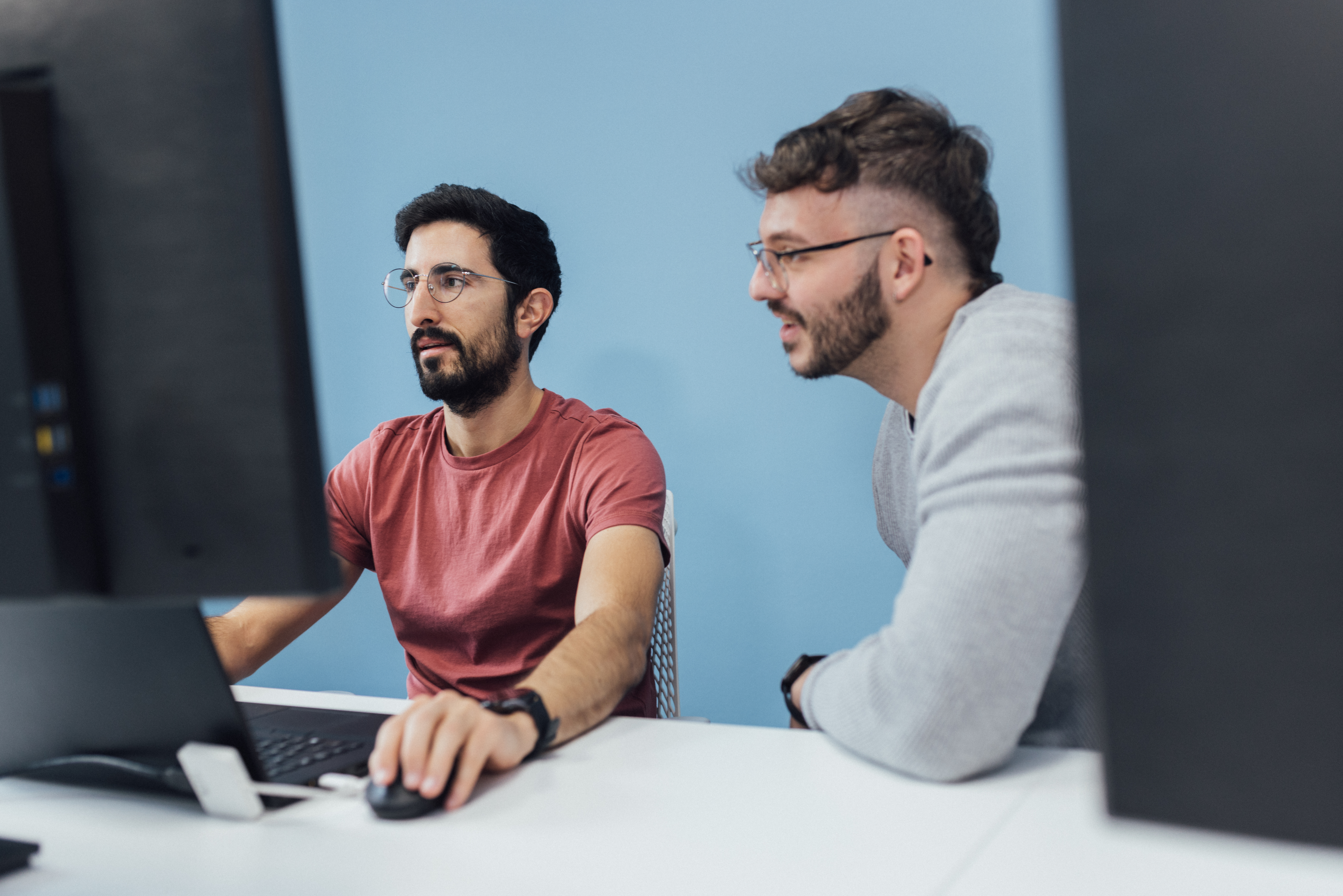Two guys talking in front of a screen.