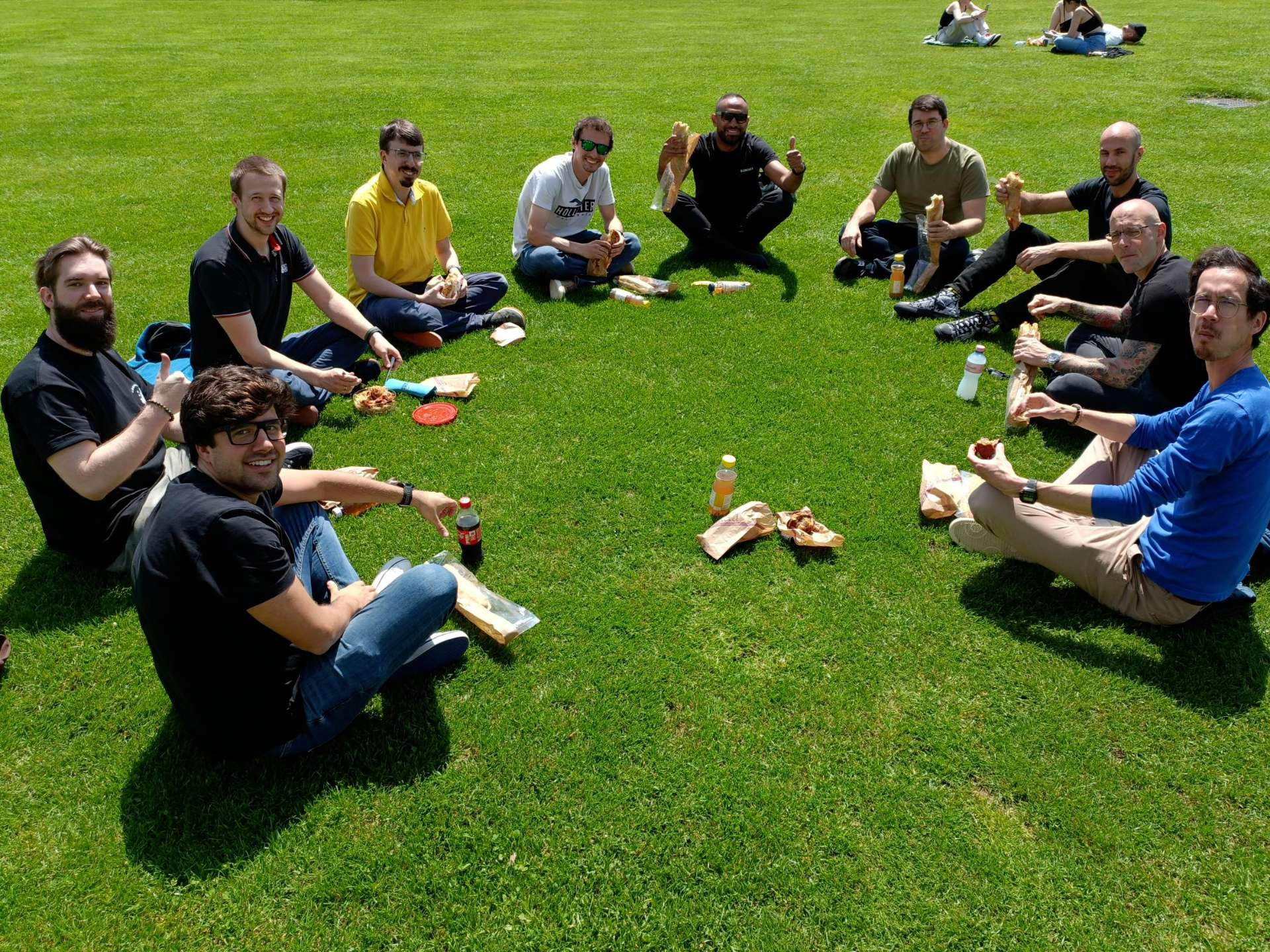 Group of smiling people sitting on the grass.