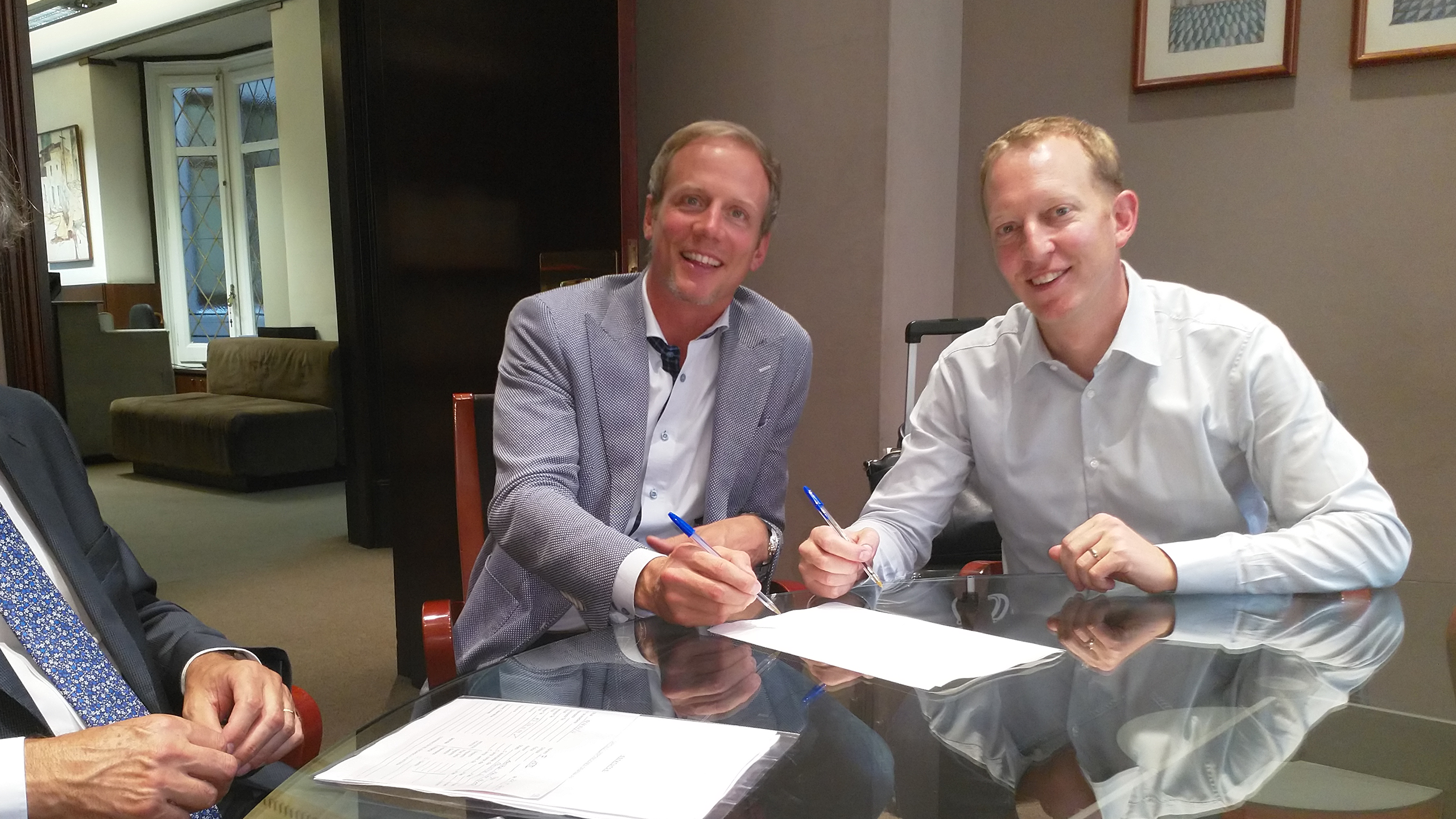 Two men sitting around a table signing a document