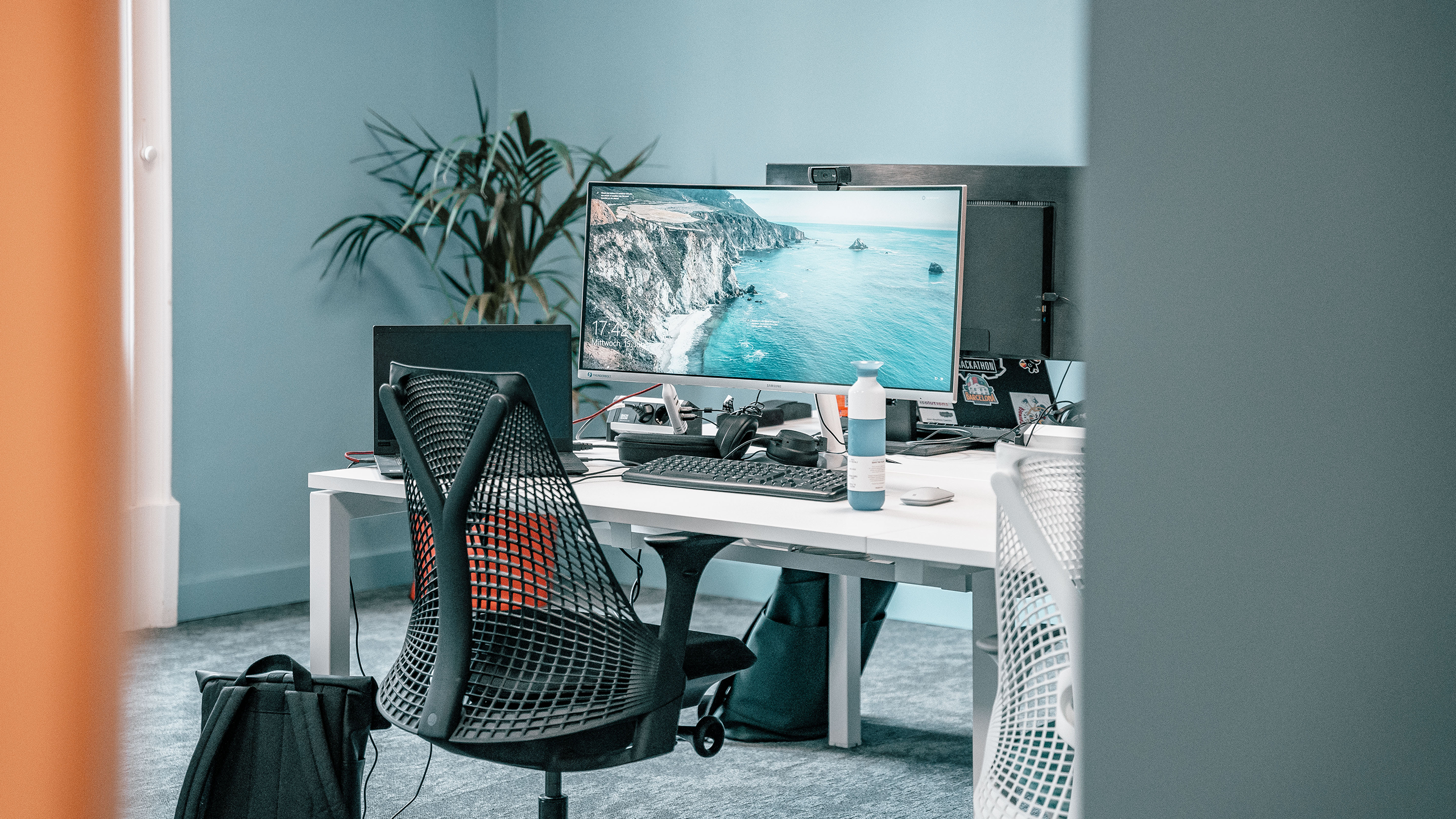 Office space with a white table, big screen and a black chair