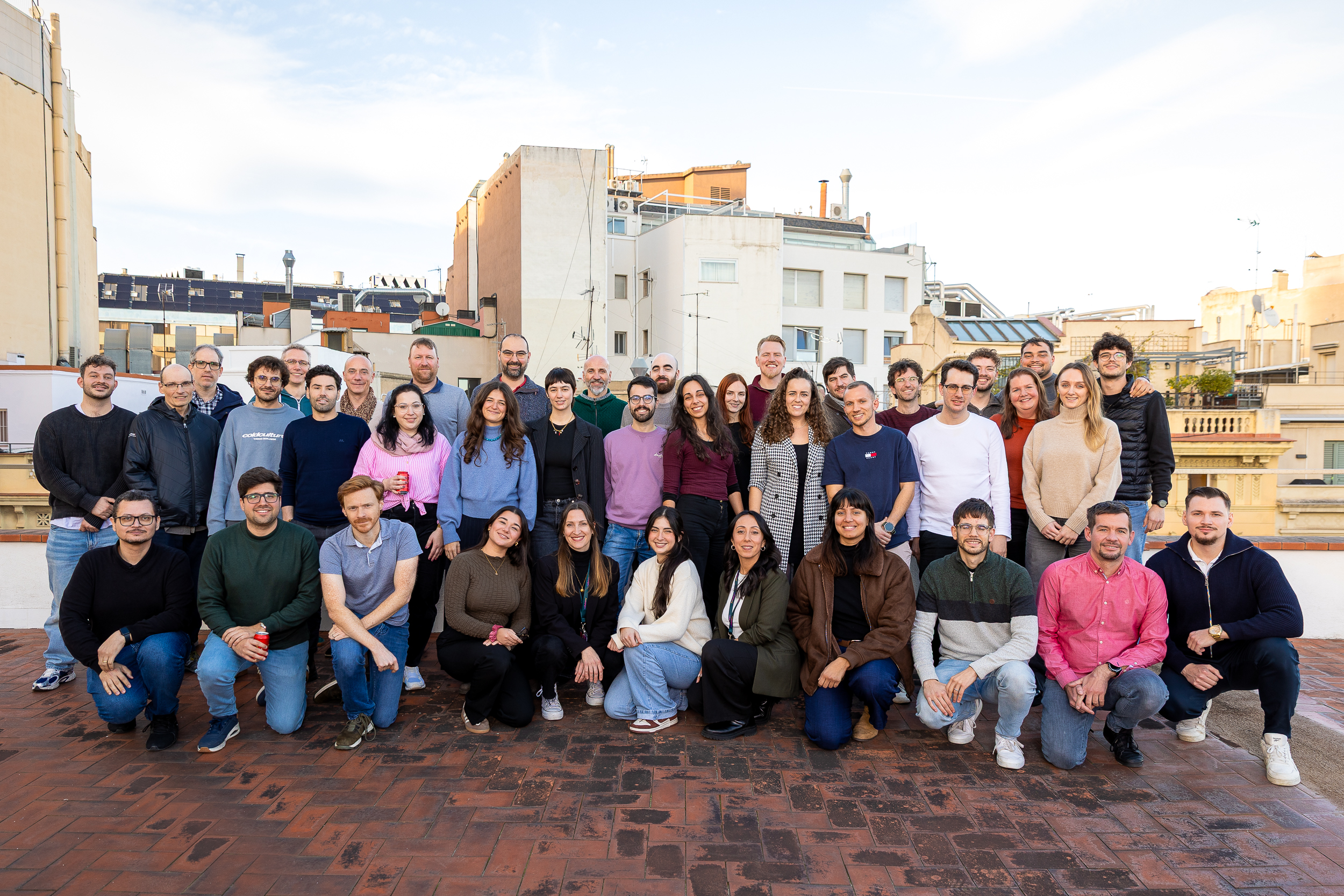 Large team group posing together on rooftop terrace in city setting
