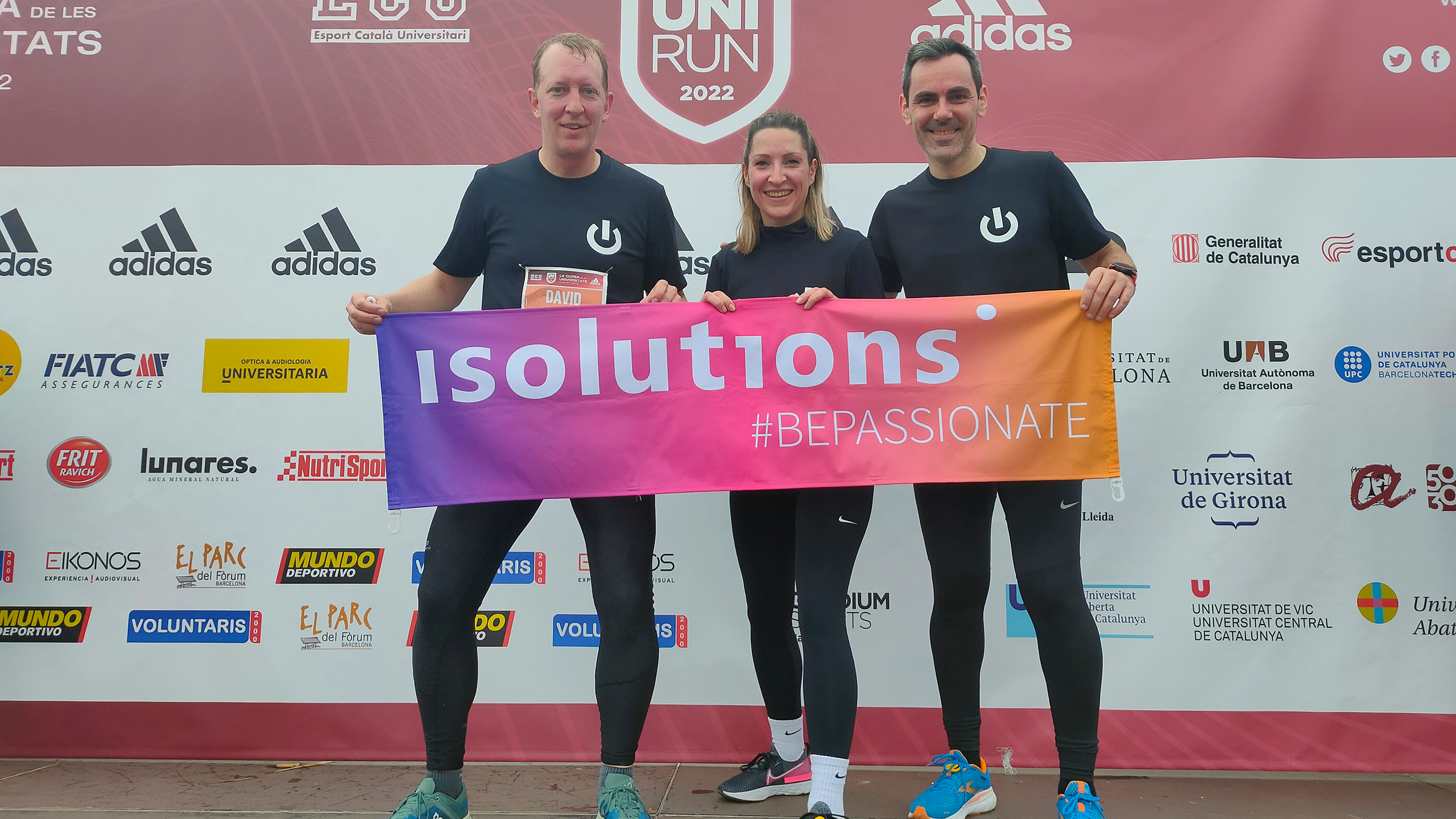 Three people holding a colourful banner after finishing a run