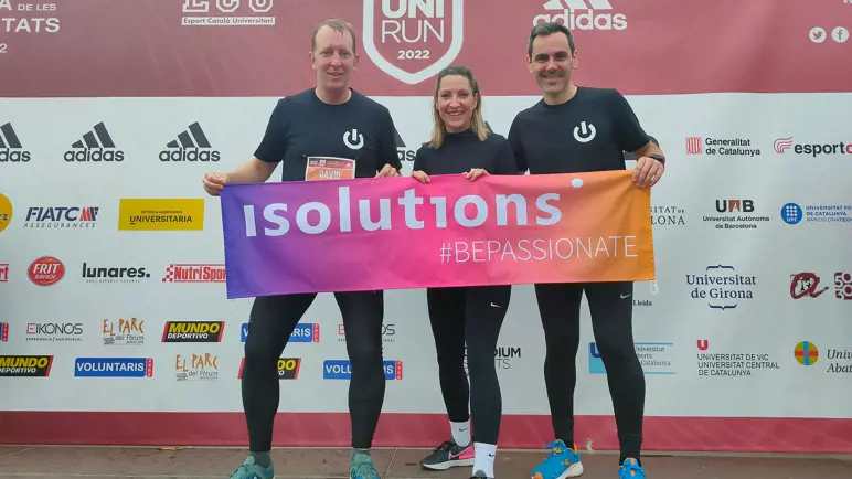 Three people holding a colourful banner after finishing a run