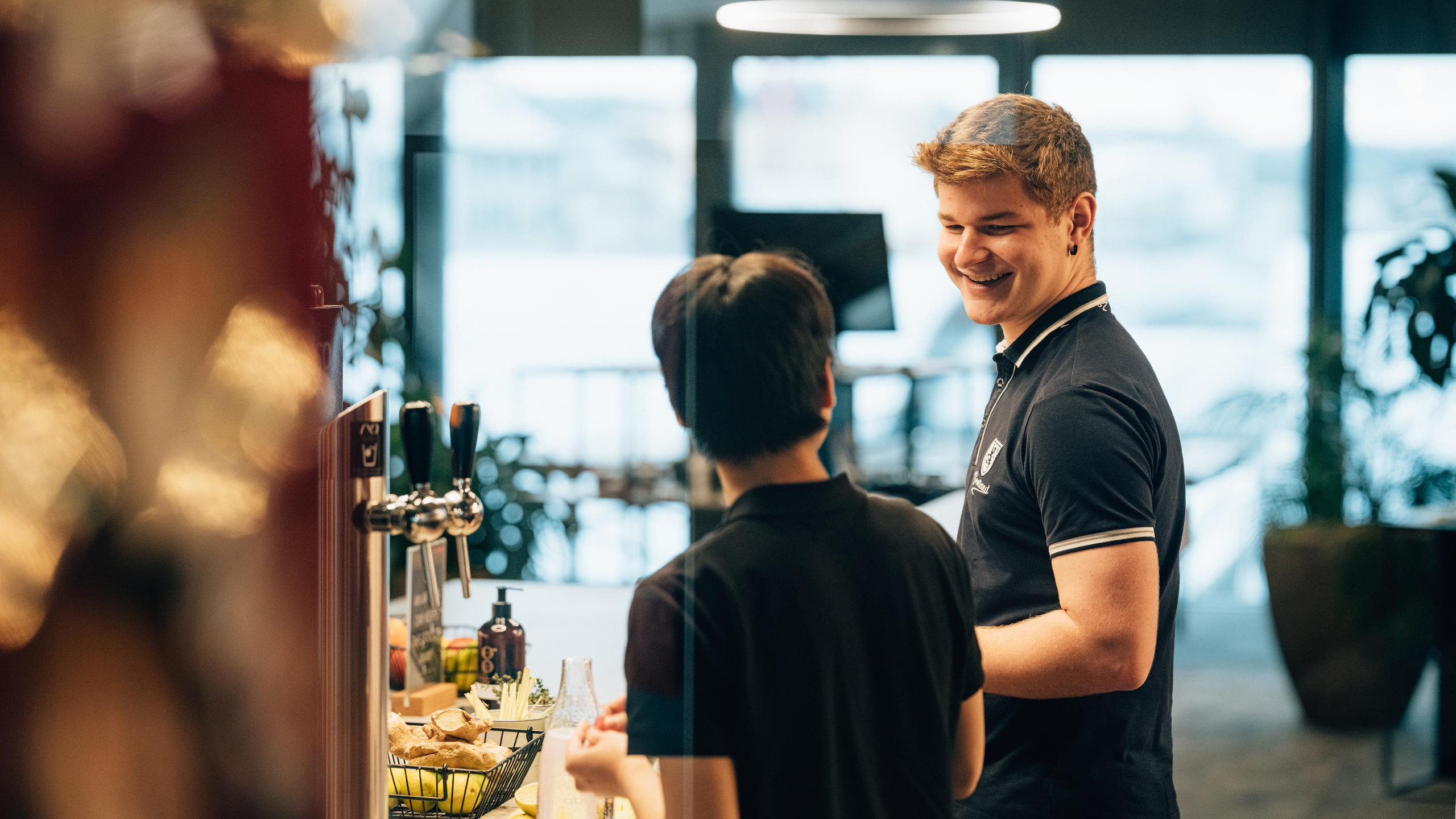 Zwei Lehrlinge vor dem Wasser-Zapfhahnen in einem Büro
