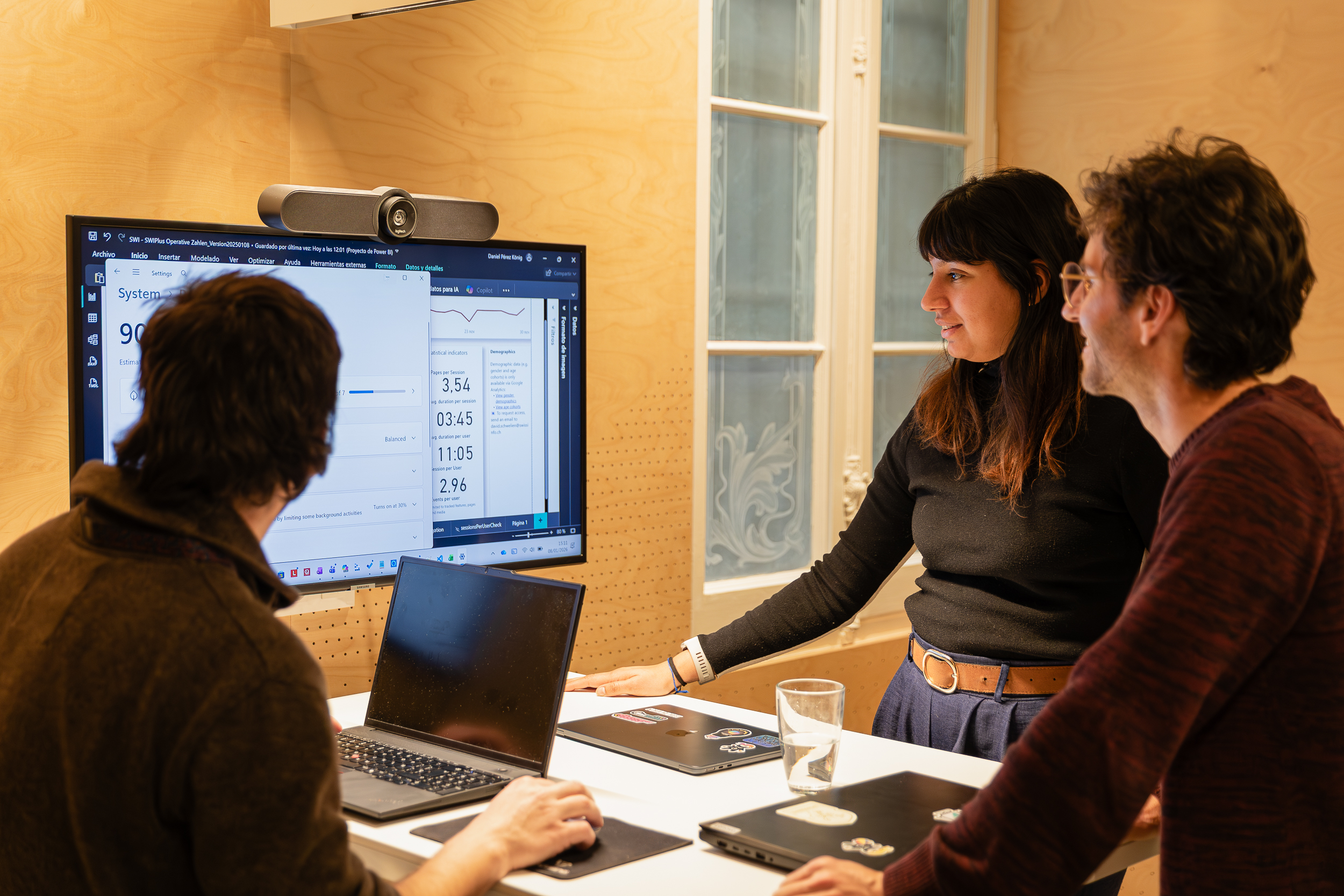 Three people collaborating in front of a screen showing data.