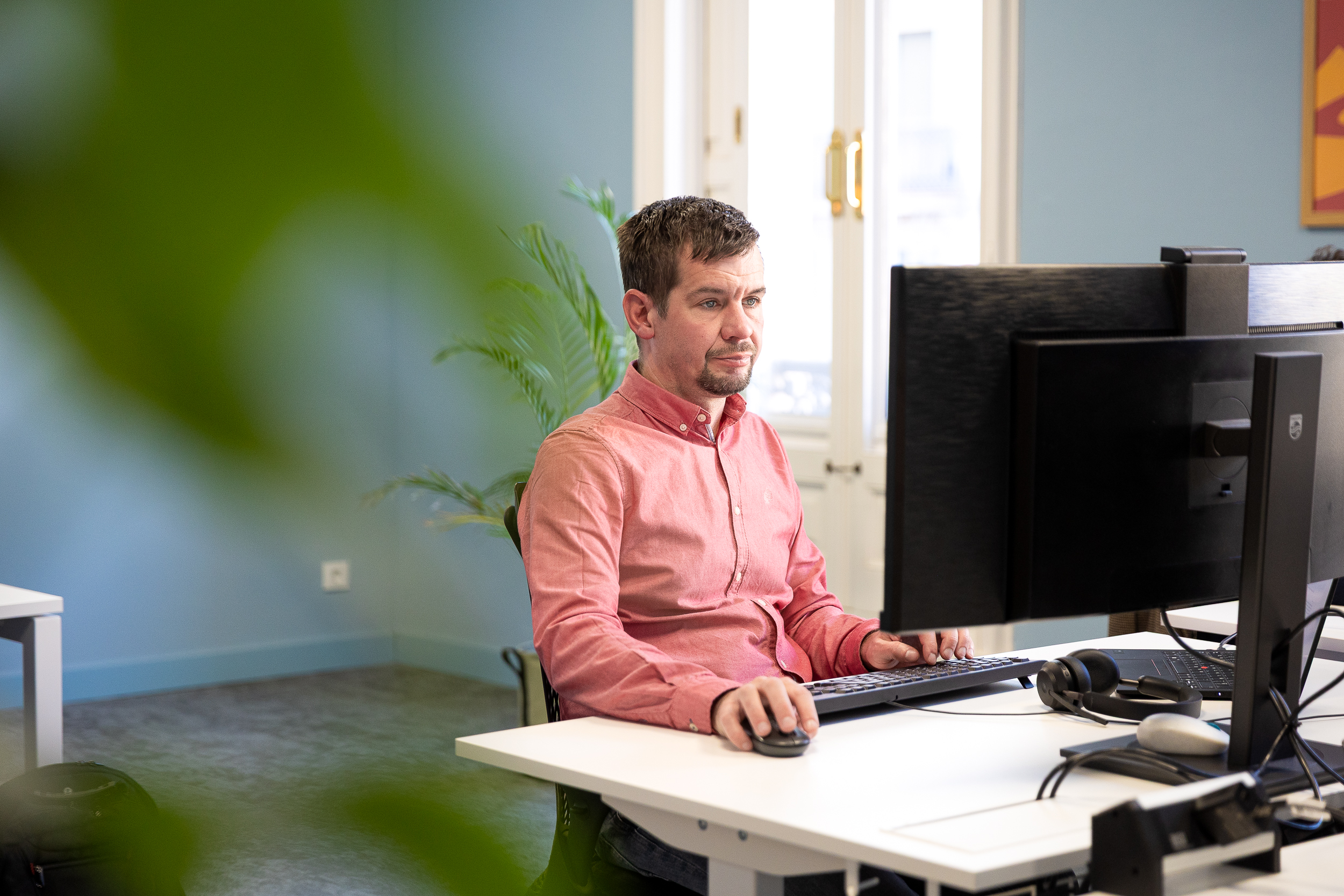 Men sitting at a desk, in front of a laptop. 