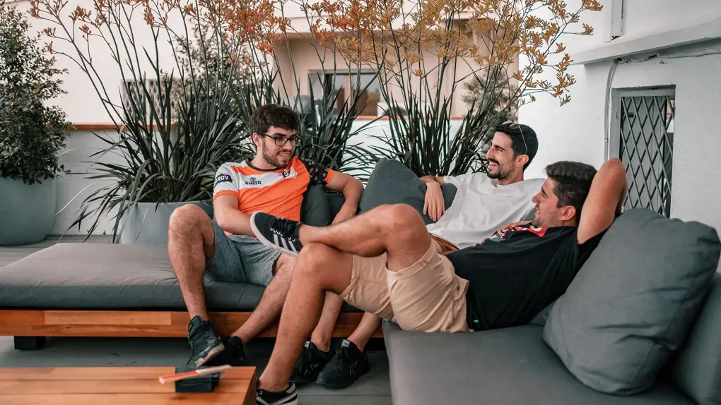 Three men sitting on a couch on a terrace having a chat