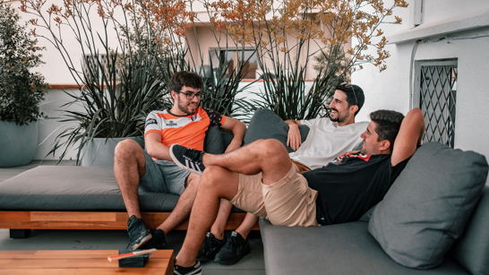 BeachBootCamp 2022 Team Break Three men sitting on a couch on a terrace having a chat