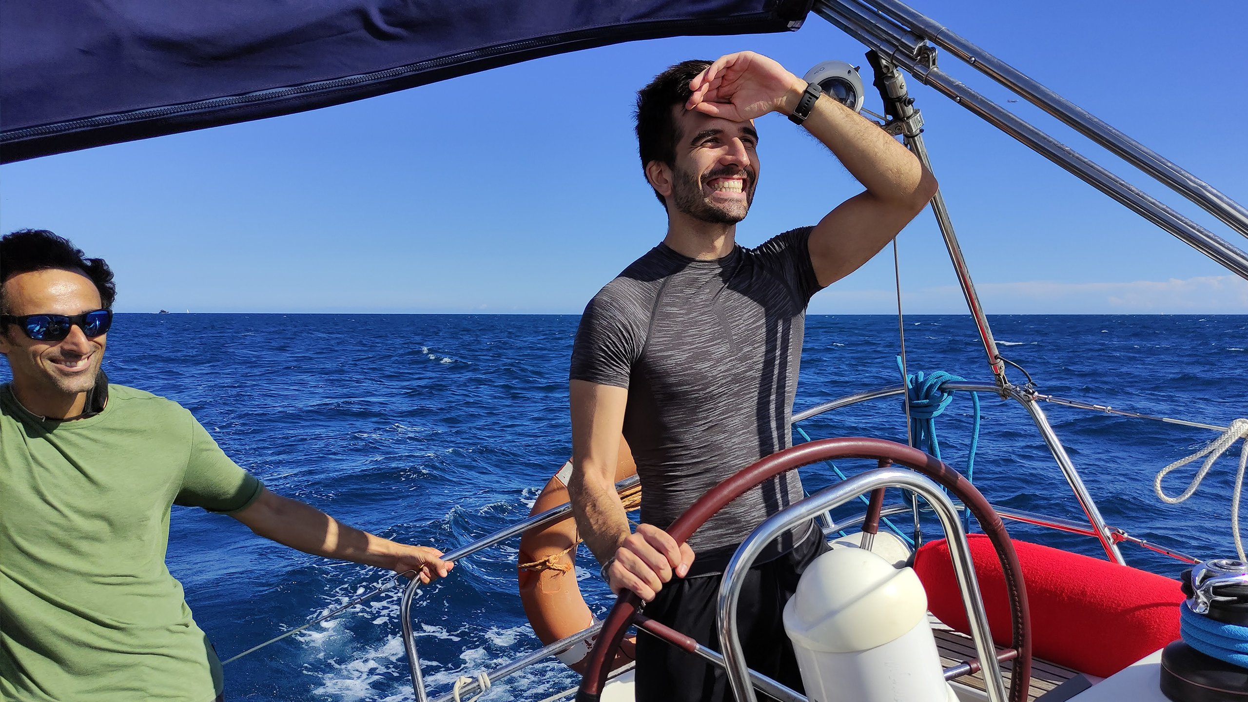 isolutions employee Dario at the helm of the boat at the regatta with the sea in the background