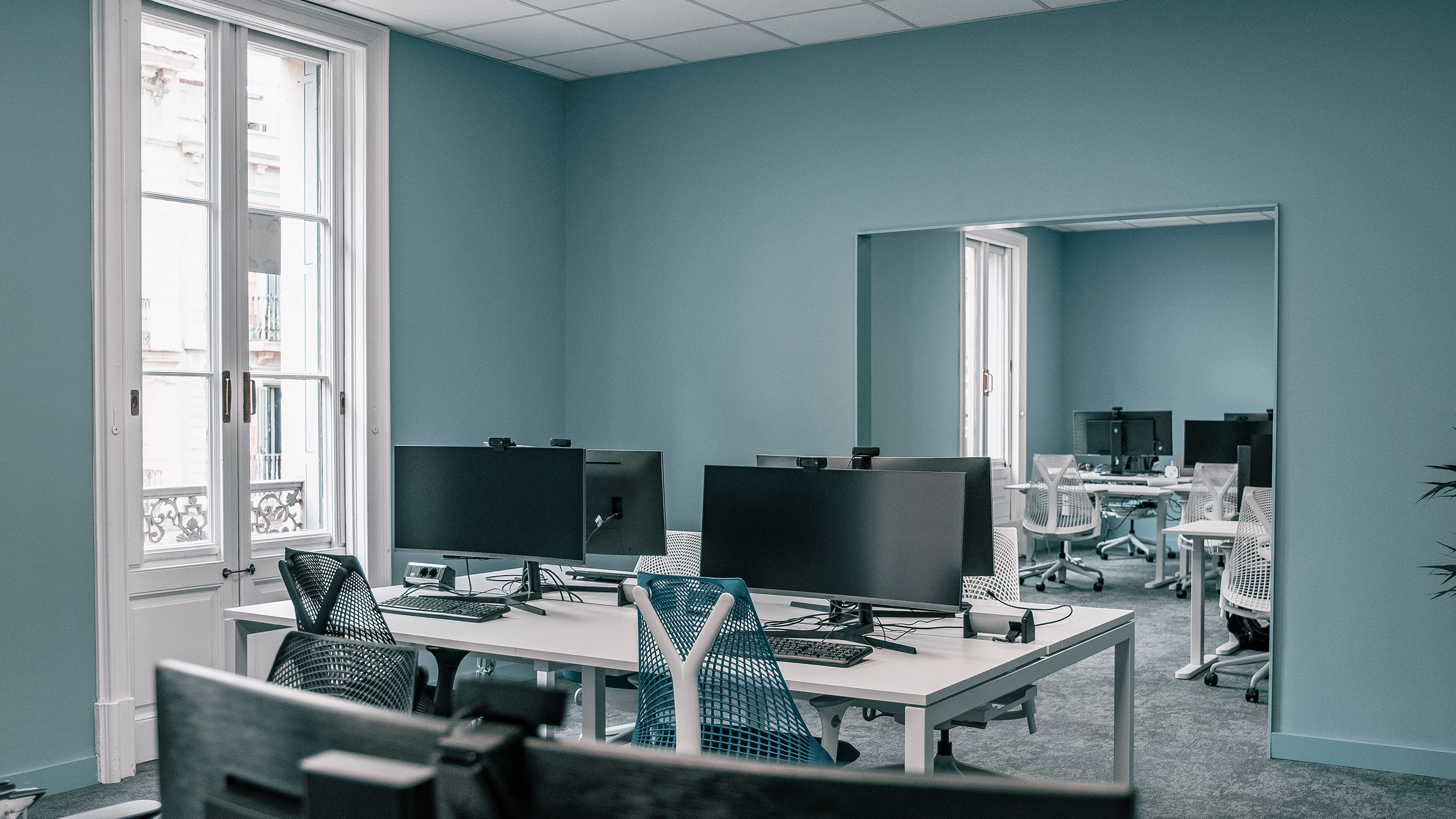 Office with blue walls and working islands with screens