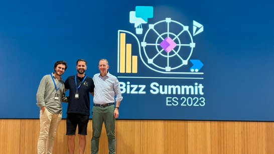 Bizz Summit Group Picture Three men standing on a stage in front of the Bizz Summit Logo 2023