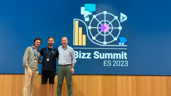 Three men standing on a stage in front of the Bizz Summit Logo 2023