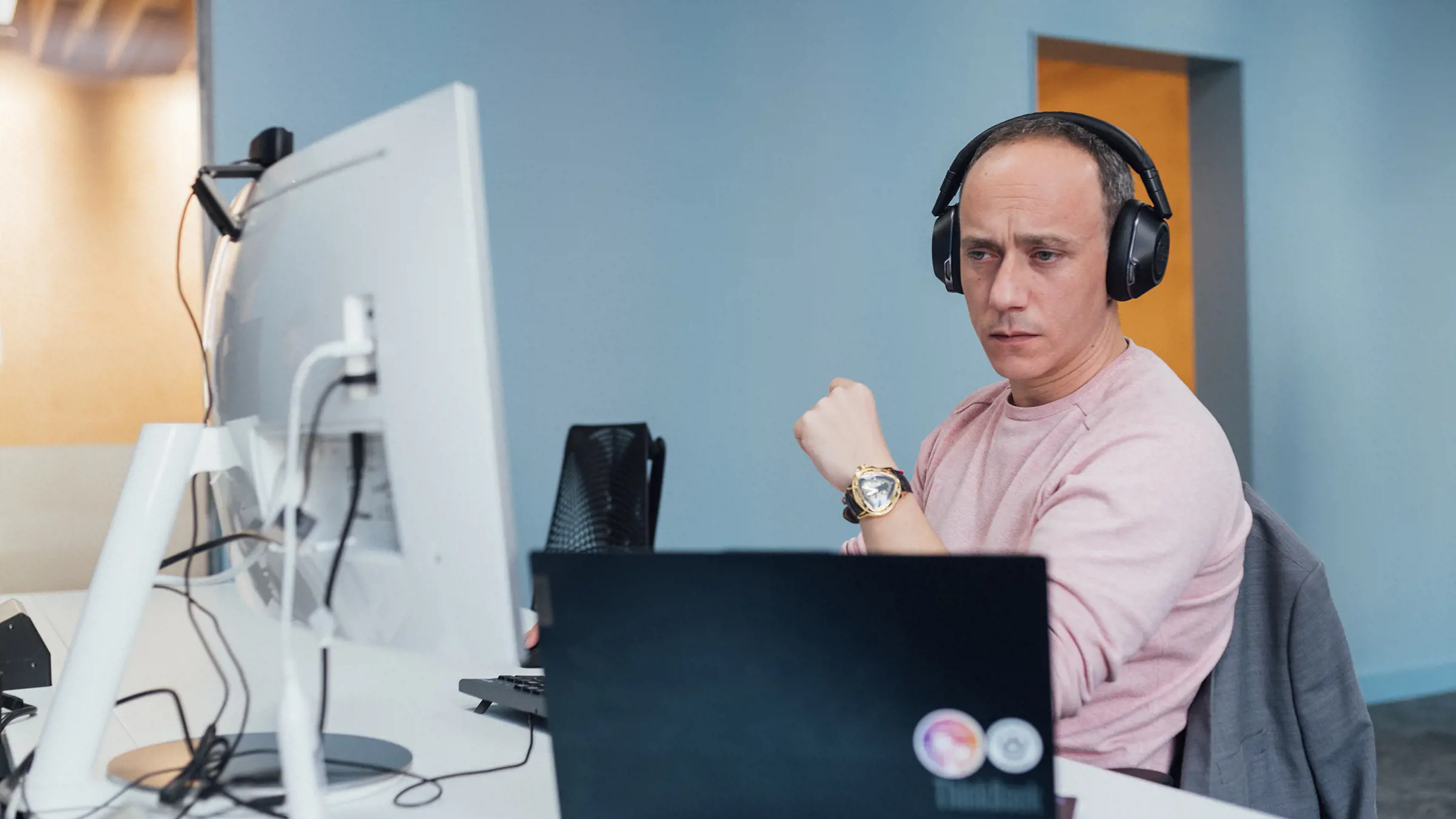 Engineer in pink pullover concentrated on working with two screens