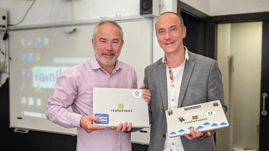 Two men standing with laptops in their hands and smiling to the camera