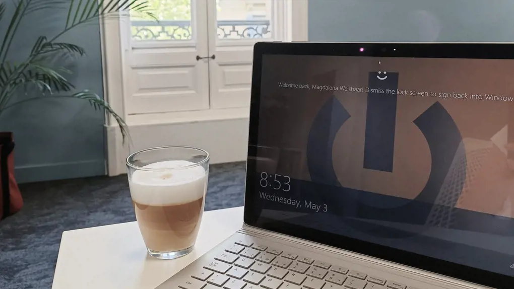 A laptop with a coffee cup on a table