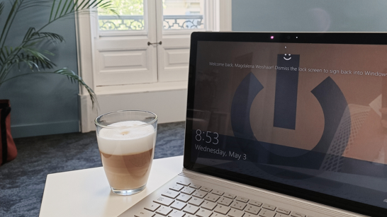 A laptop with a coffee cup on a table