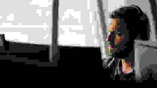 Data Analytics Power BI Frontansicht von jungem Mann am PC mit Headset schaut Data Analytics/Power BI an