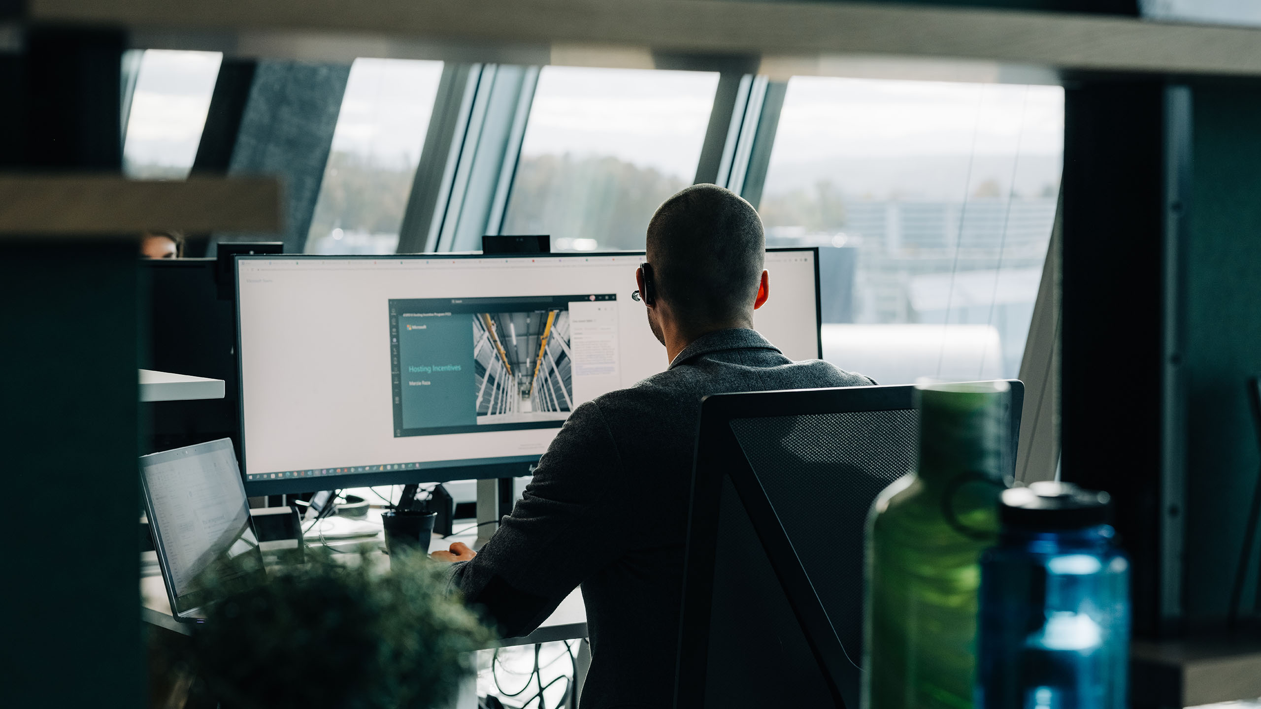 Junger Mann von hinten, wie er am PC sitzt und arbeitet
