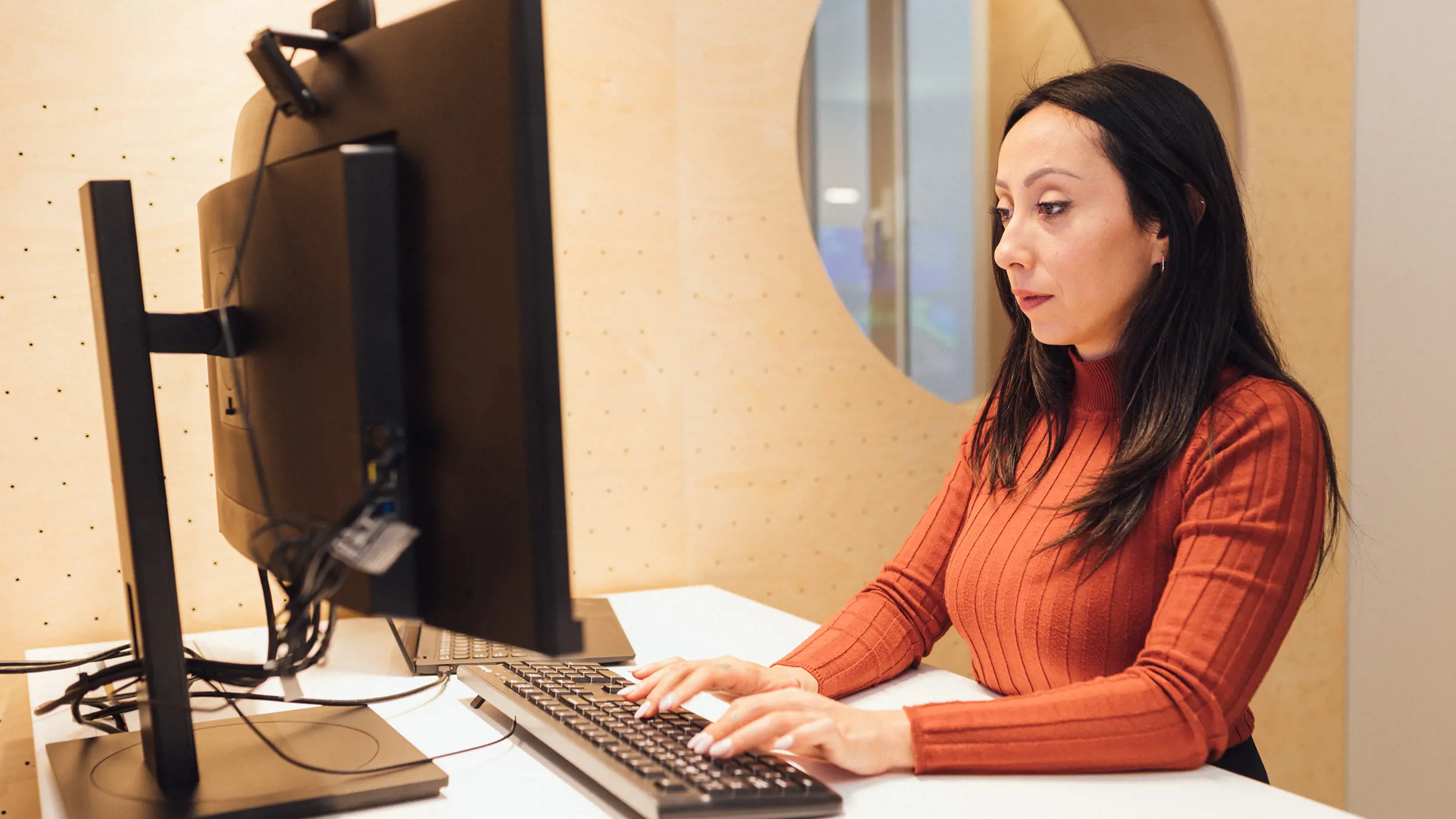 Woman with a red jumper working on a screen 