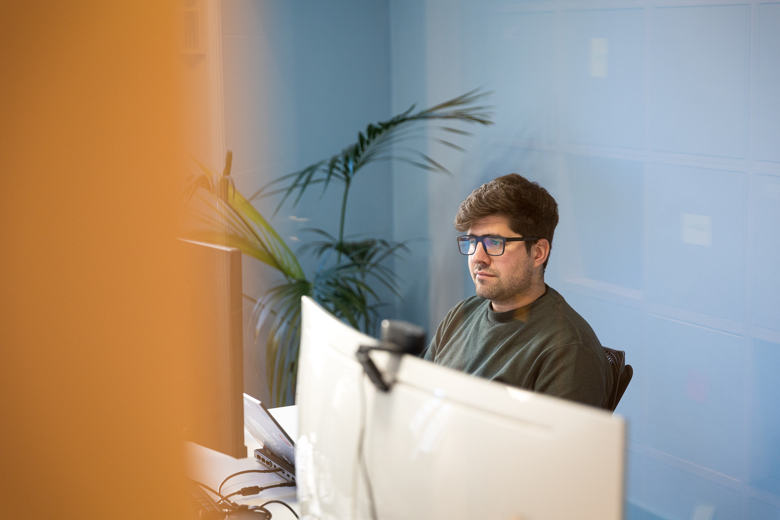 Person sitting on a desk in front of a screen.