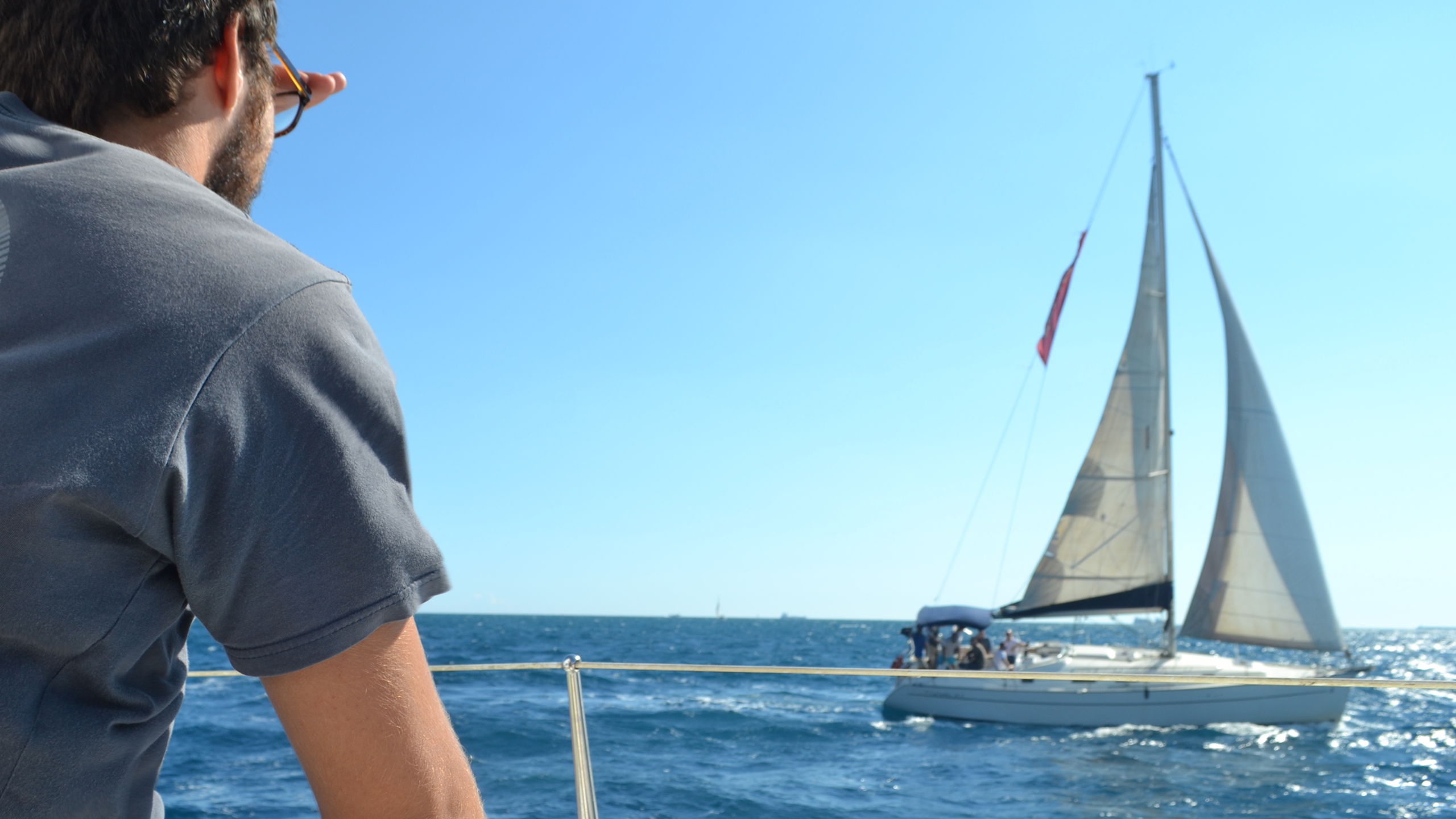 isolution's employee on a boat looks at another sailing ship on the sea