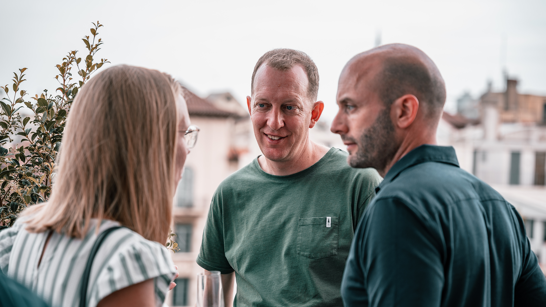 A woman and two men having a conversation outdoors during summer