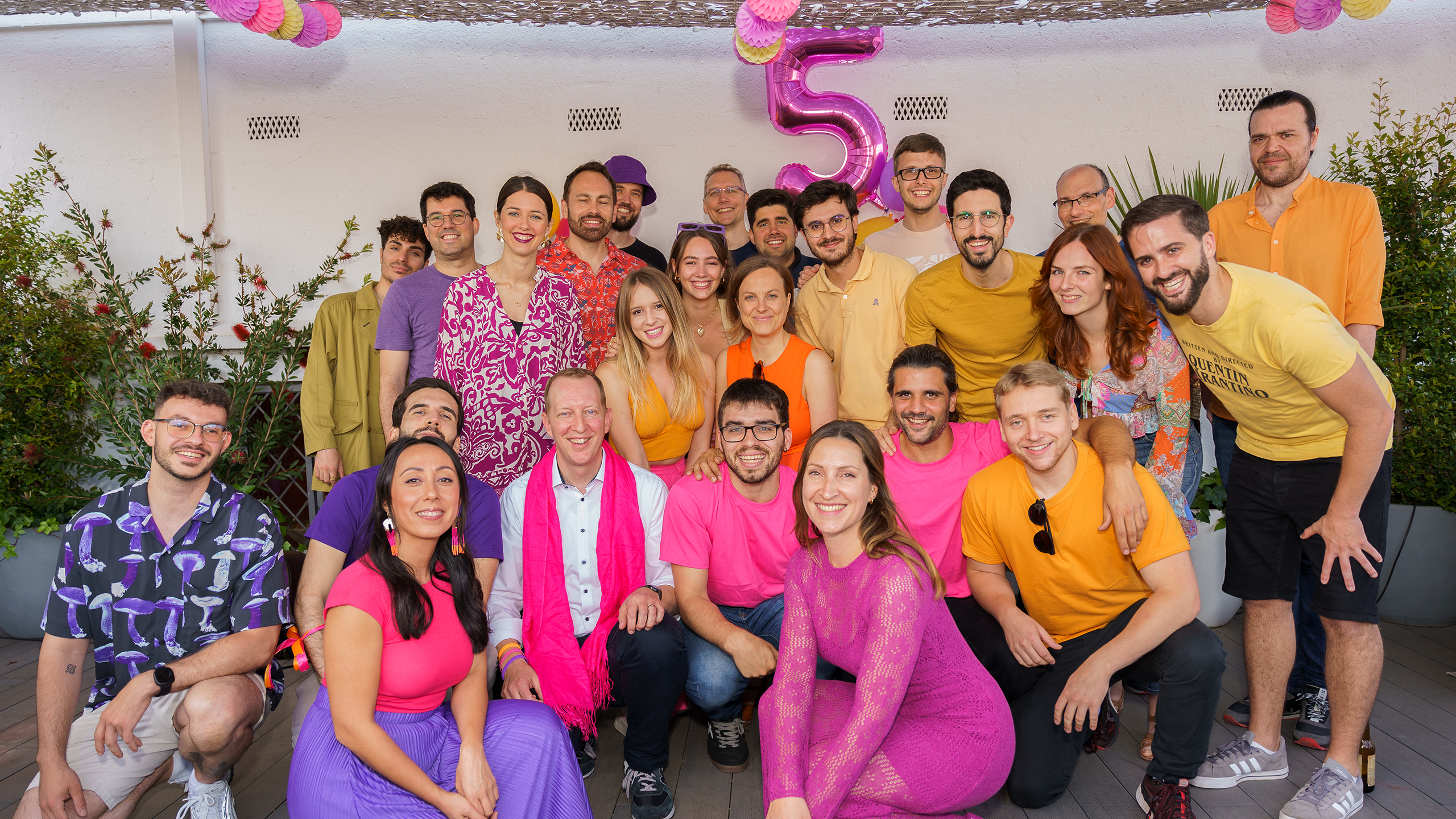 Team picture on a terrace with people dressed in pink, purple and orange