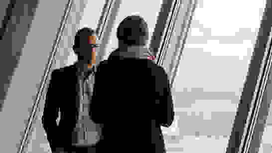 Cloud Services Mann und Frau vor Fensterfront besprechen Angebote für Cloud Services