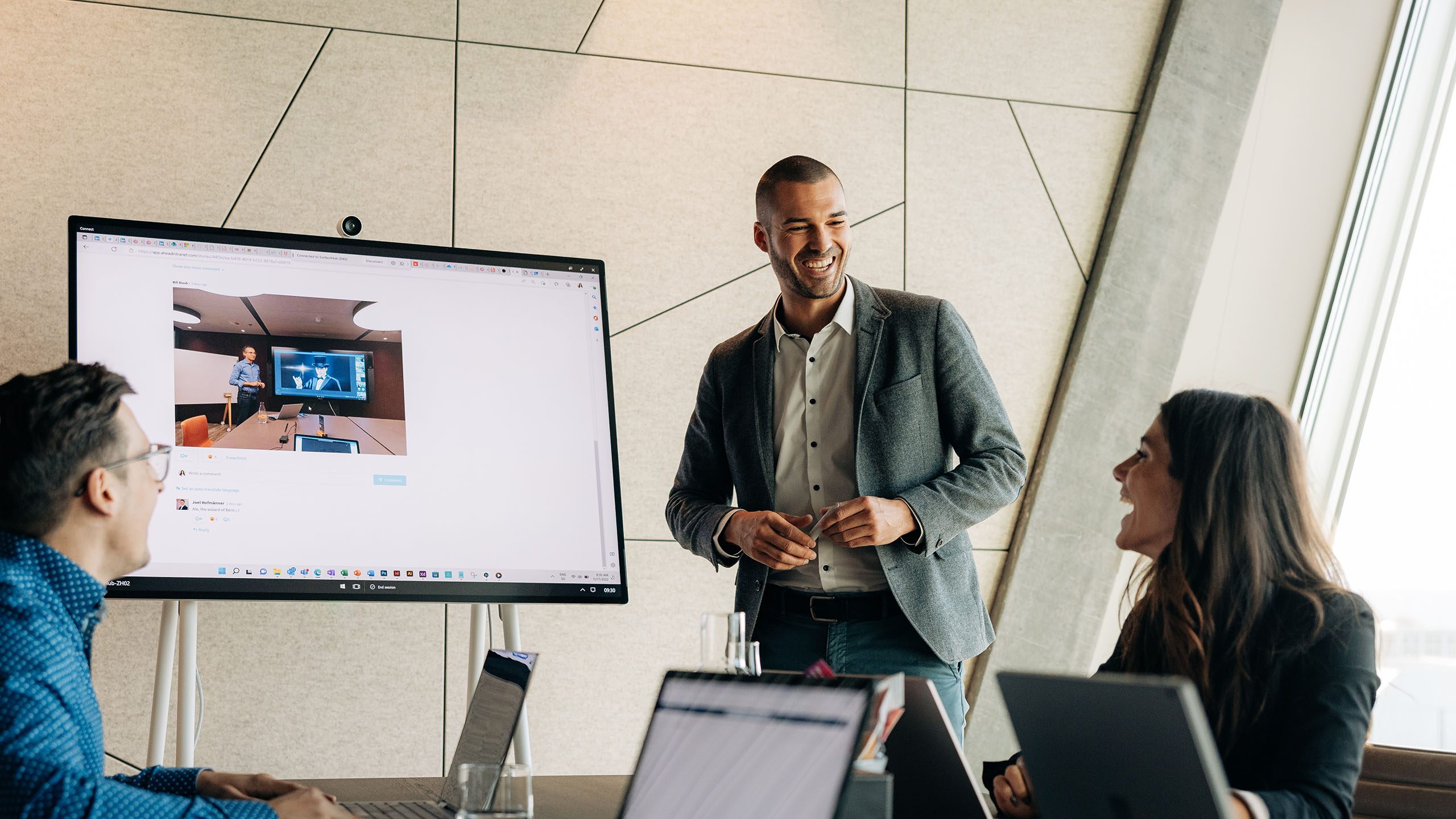 Junger Mann leitet eine Sitzung, wo alle am Laptop sind und sich anlachen