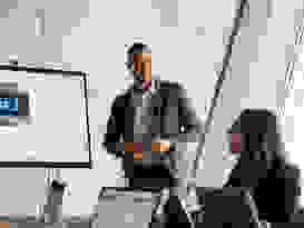 isolutions Extrameile Junger Mann leitet eine Sitzung, wo alle am Laptop sind und sich anlachen