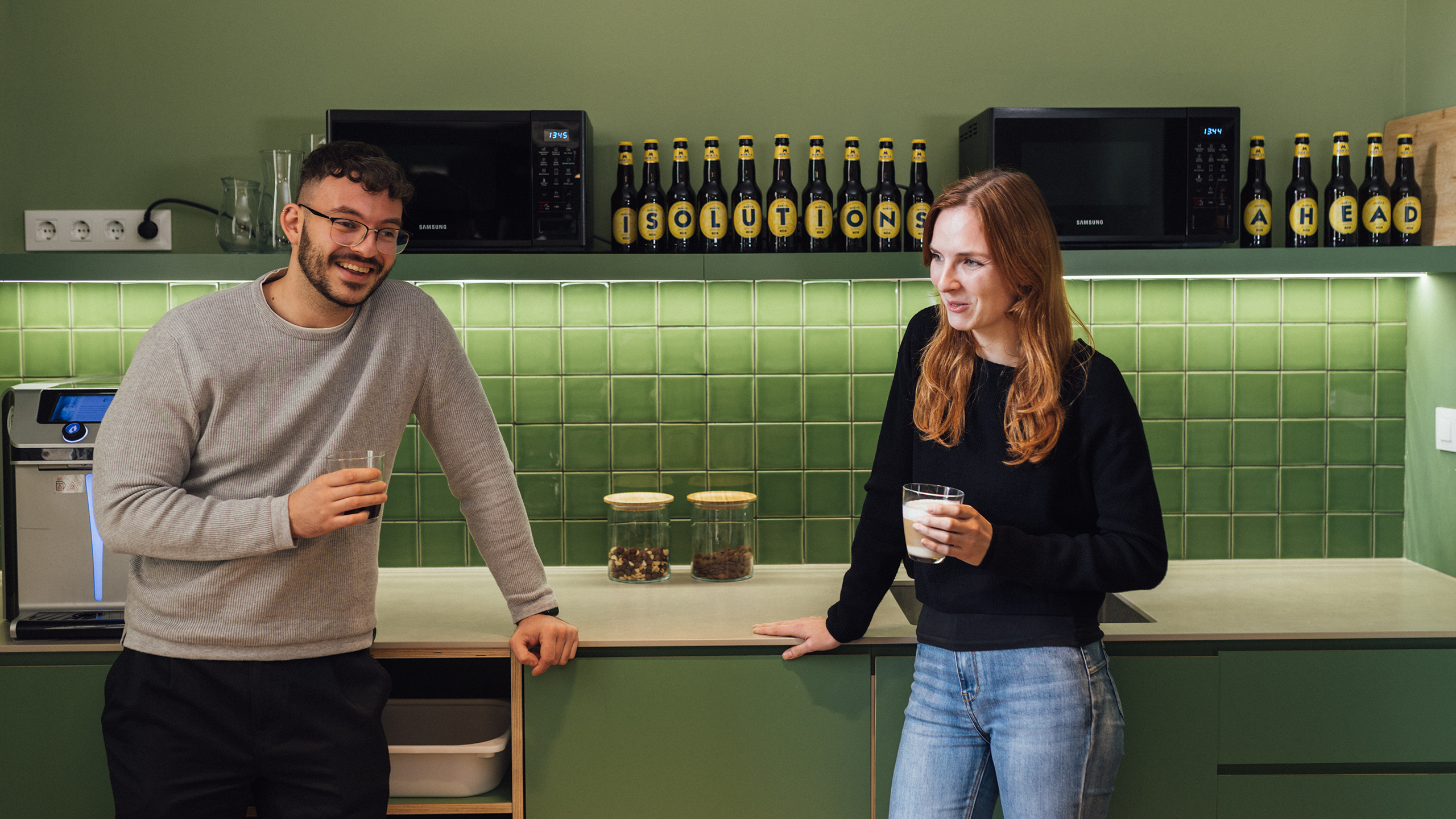 Employees having a coffee standing in a green kitchen