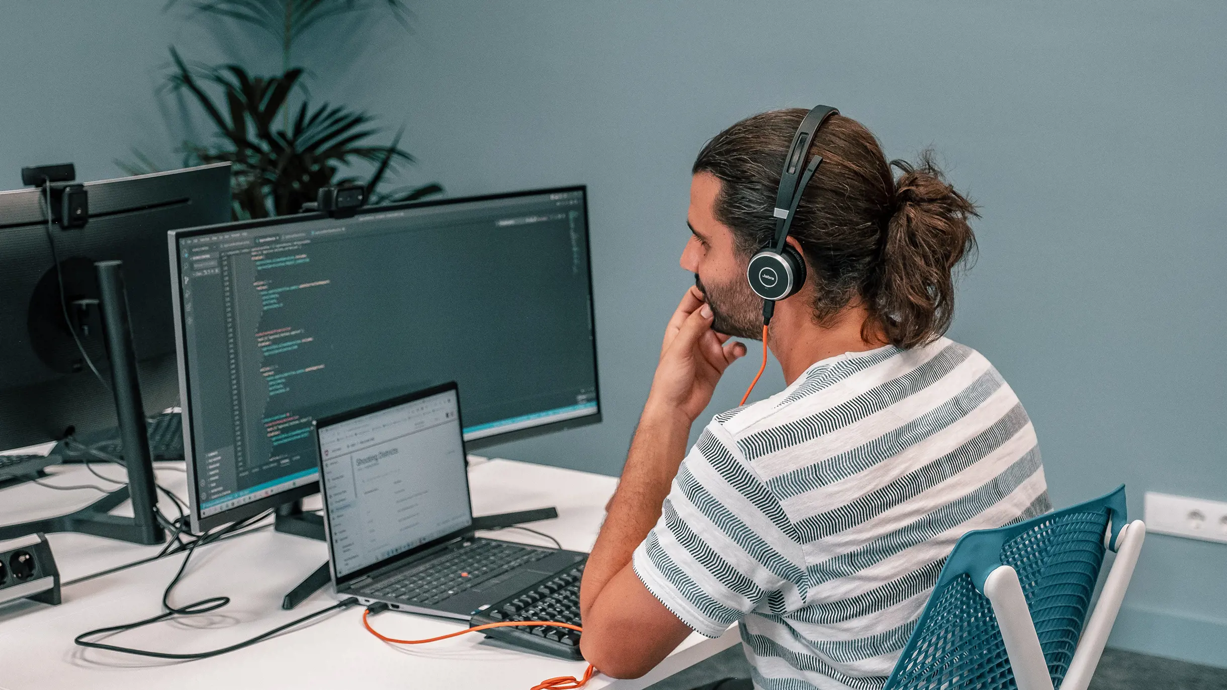 Software Developer with headset working on two screens 