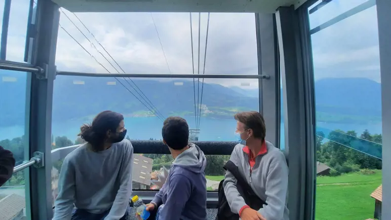 Three men watching out of a cable car in the Swiss mountains