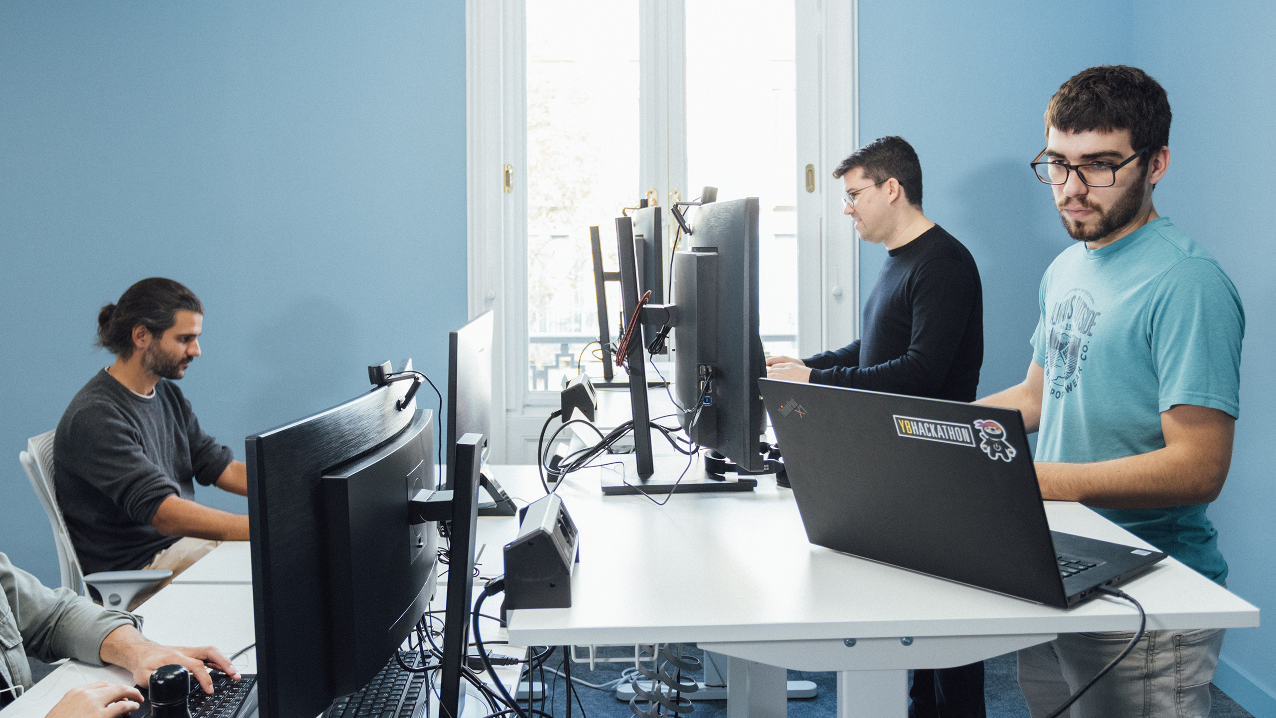 Three software developers working on sit and stand desks