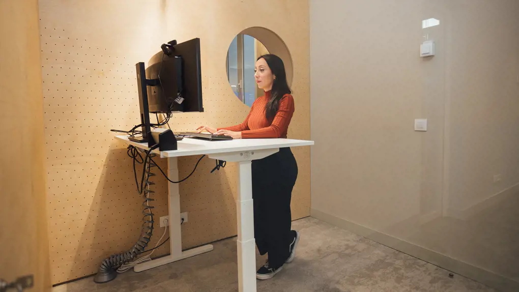 Woman working on a standing desk in front of a PC