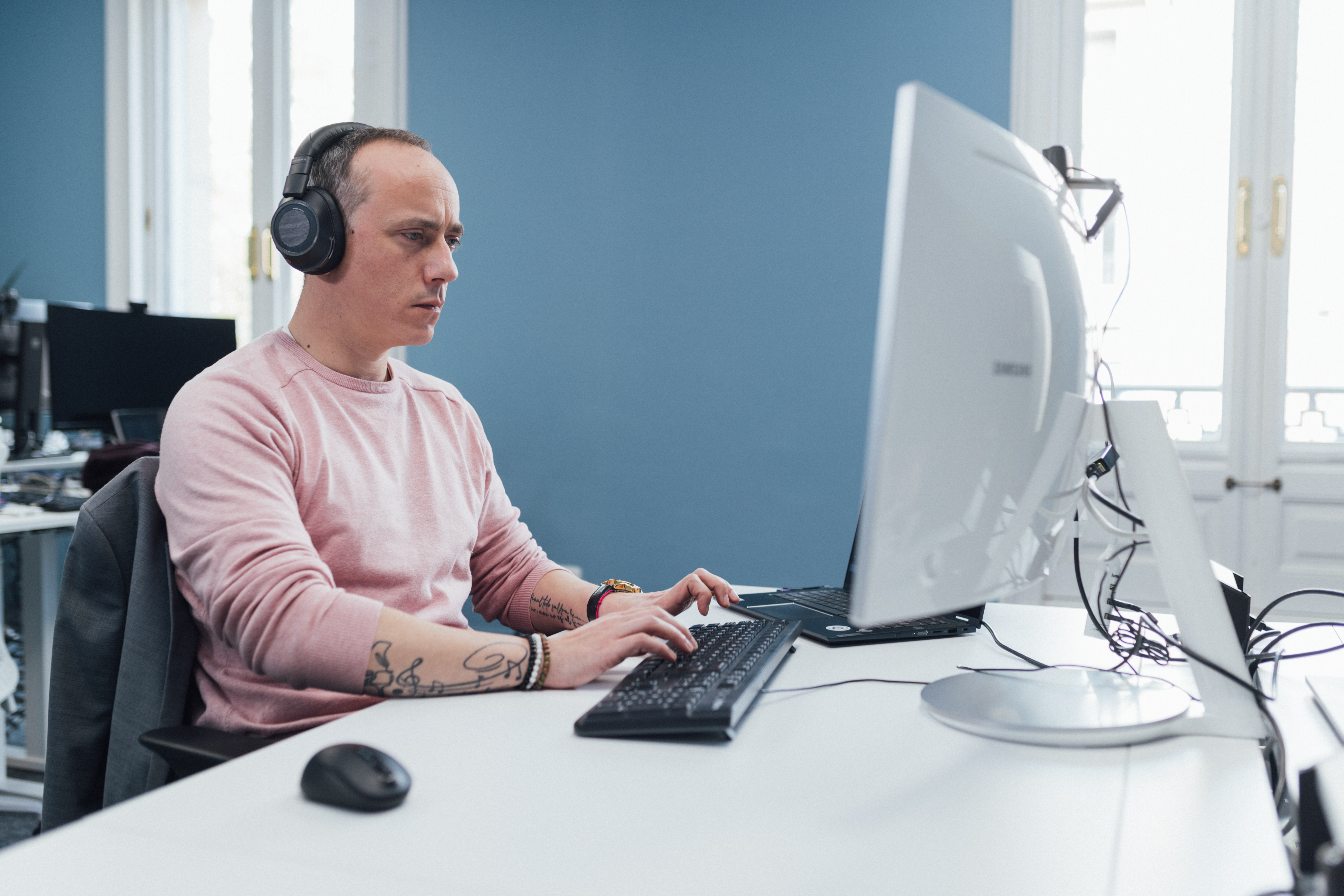 Man sitting at a desk, in front of a laptop.