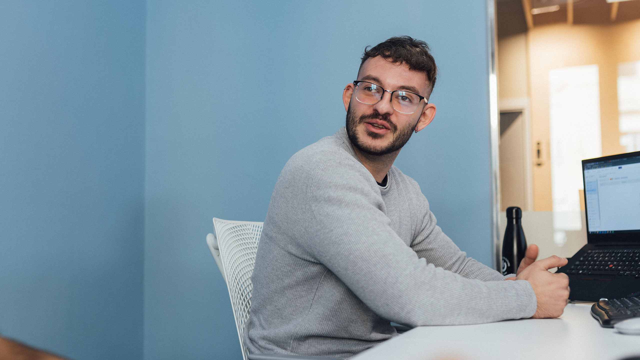 Software developer in grey jumper and glasses happily at work 