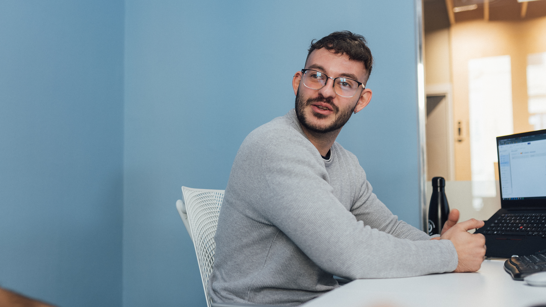 Senior Software Developer Software developer in grey jumper and glasses happily at work