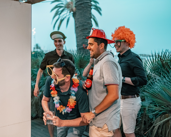 Events are in our DNA Group of people taking pictures with funny hats in front of a photo booth