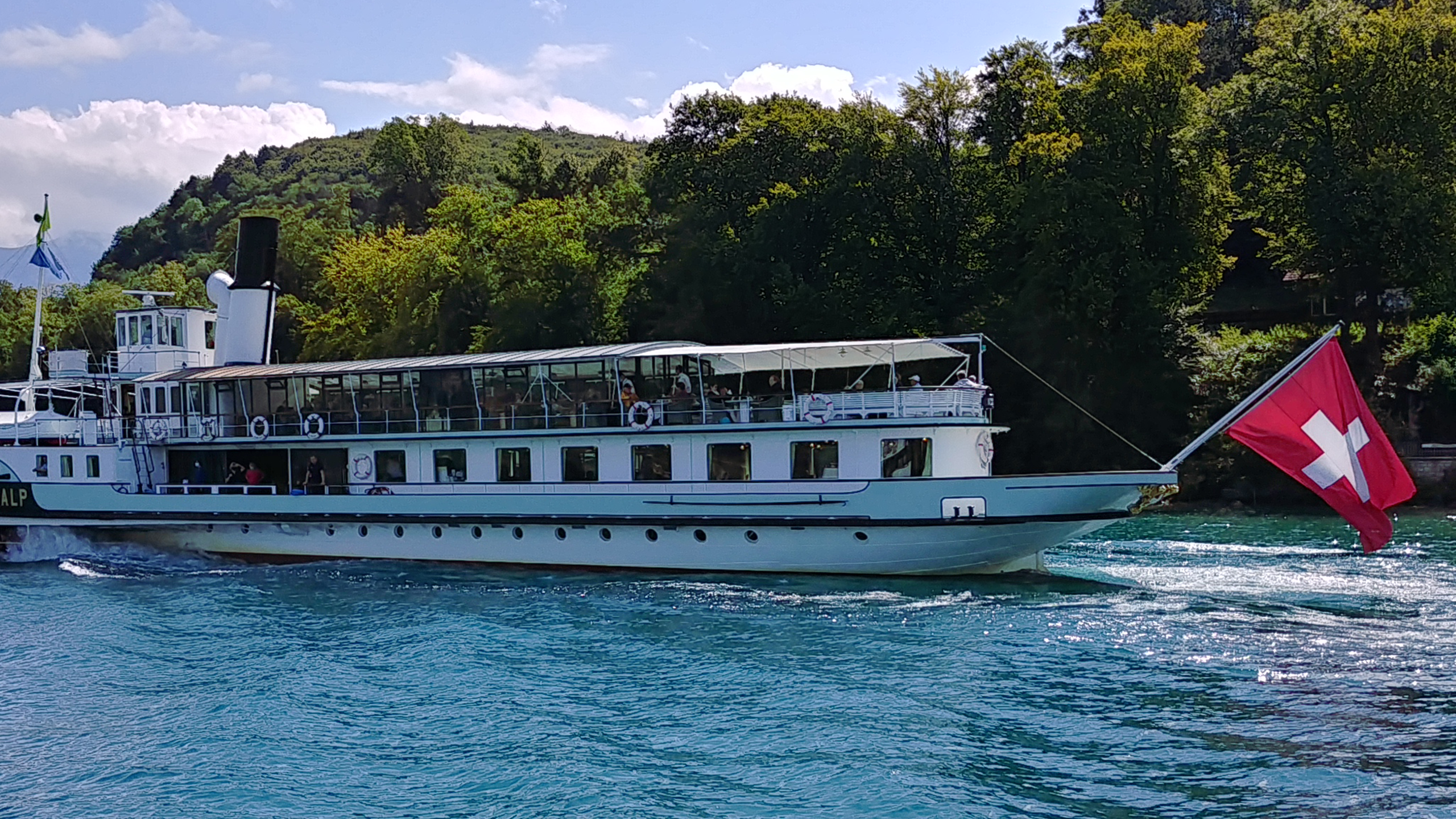 White boat with a Swiss flag on a lake